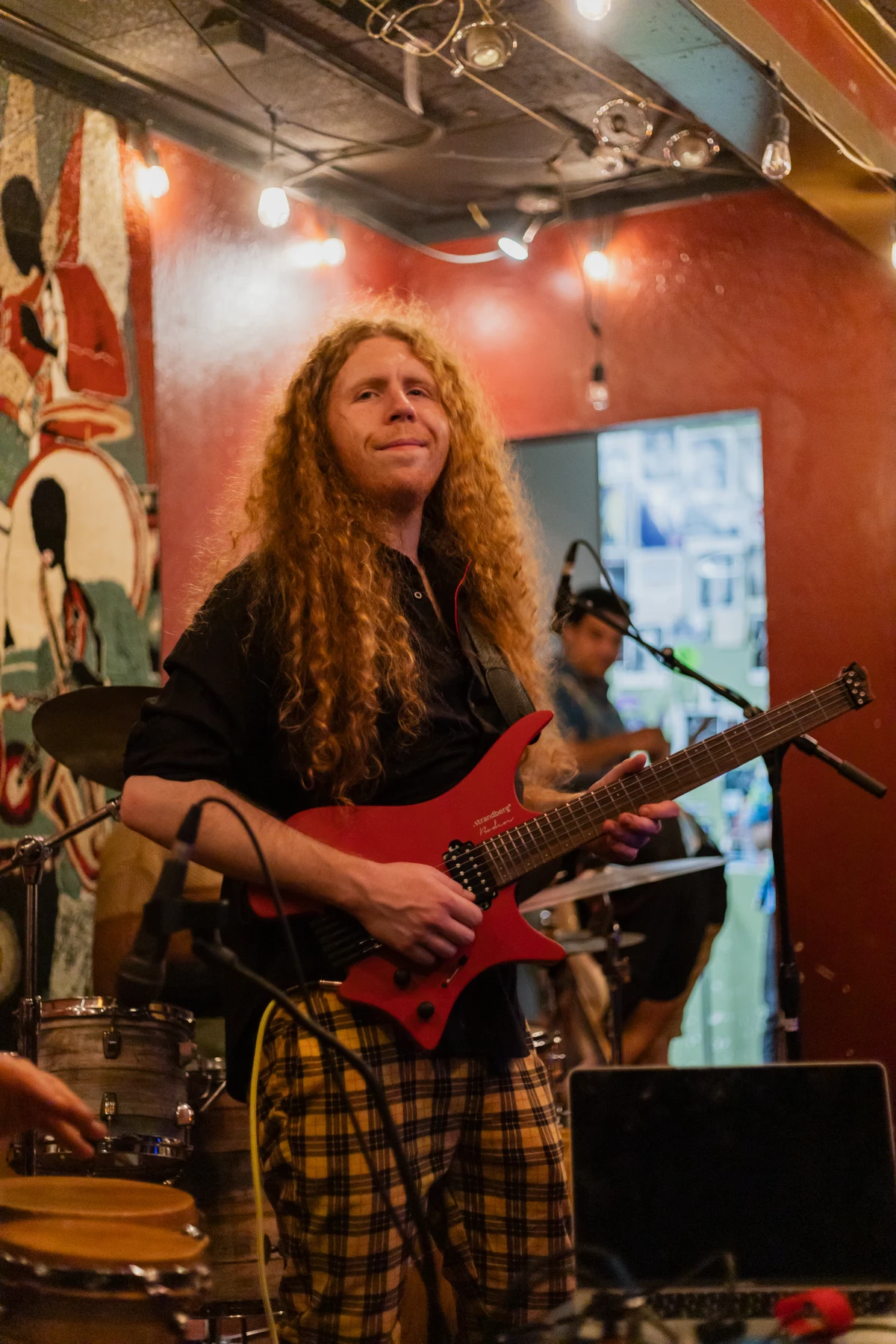 Sean playing guitar onstage at the Torch Club under red stage lighting.
